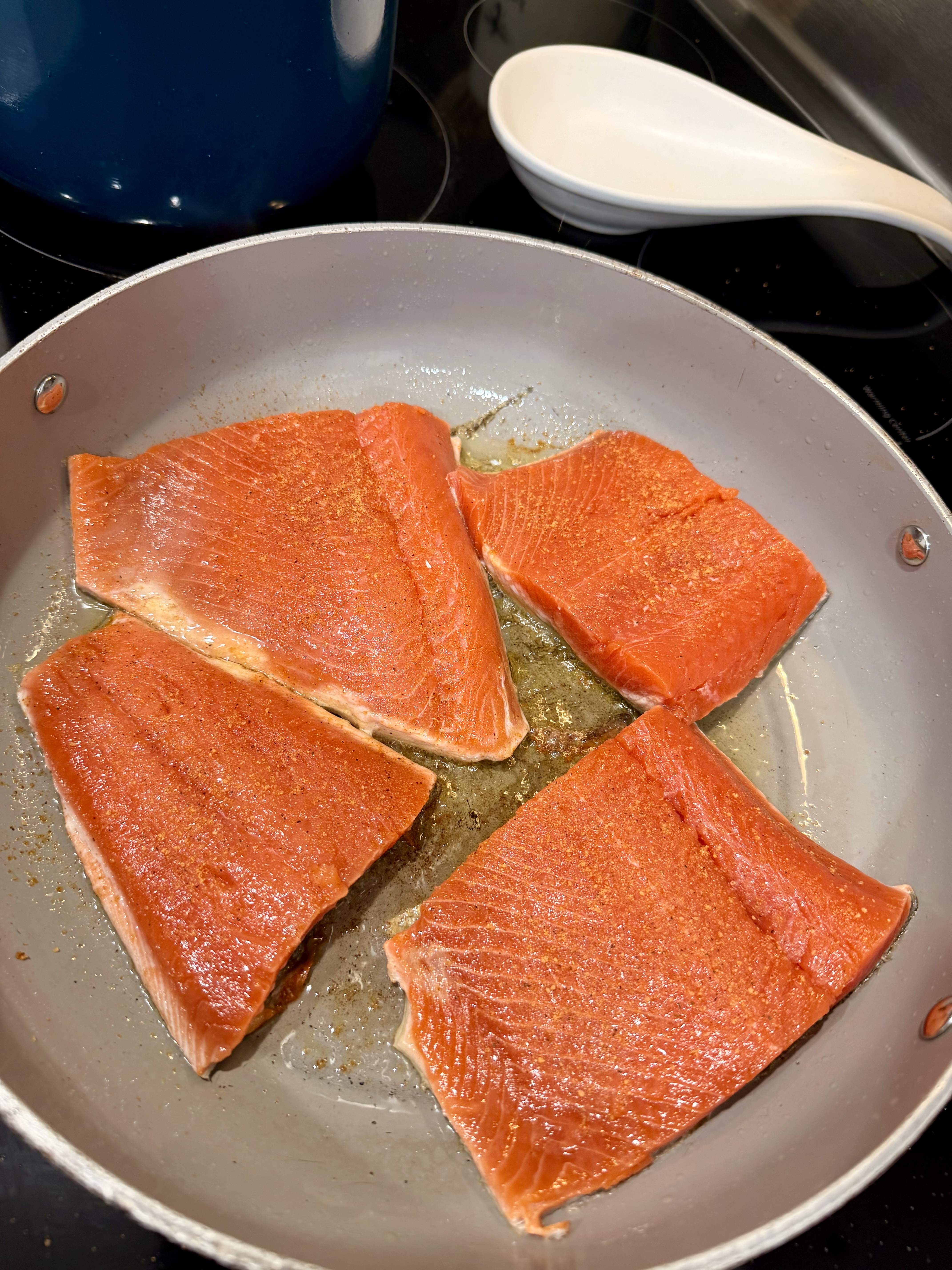 Salmon portions cooking in a skillet with Floridian seasoning